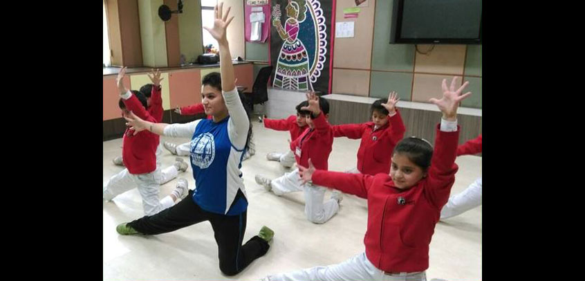 the image shows teacher teaching dance to girl students,school with theatre
