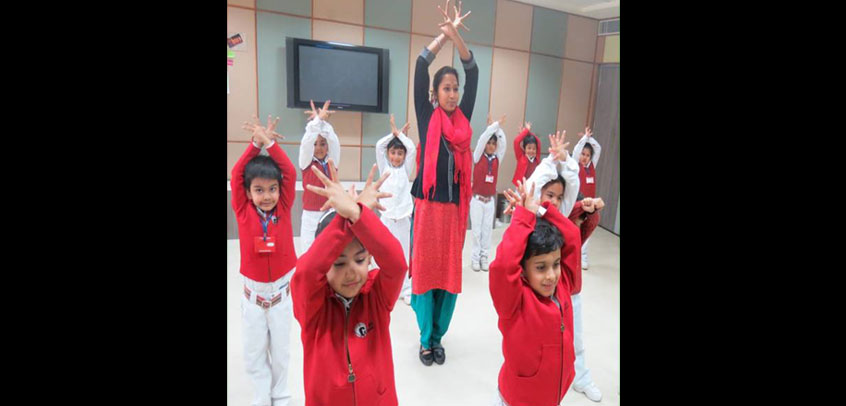 the image shows teacher teaching dance to girl students,school with theatre
