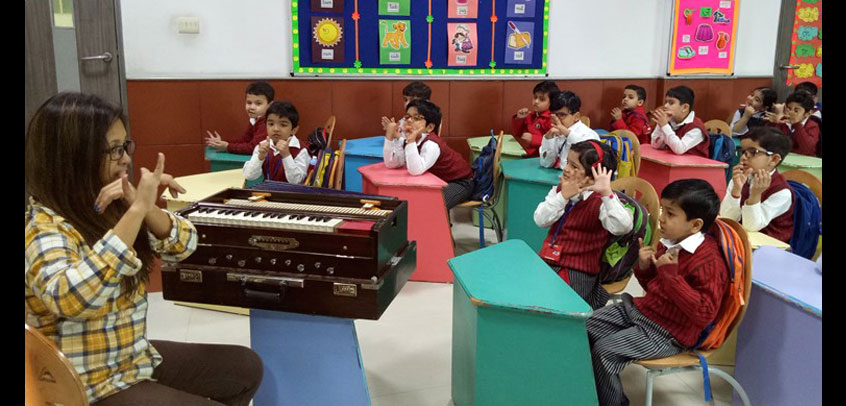 top school in extra curricular activities, students of junior wing learning music lessons from their teacher
