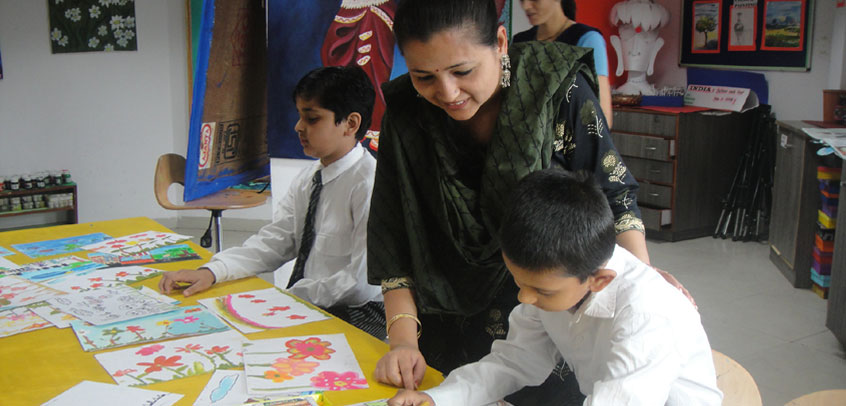 best school in extra curricular activities,the image shows teacher helping students in arts class
